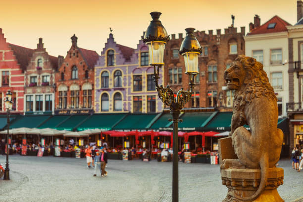 Traditional Belgian Lion Statue in front of City Hall and Colorful Brick Buildings in Market Square, Bruges, Belgium stock photo