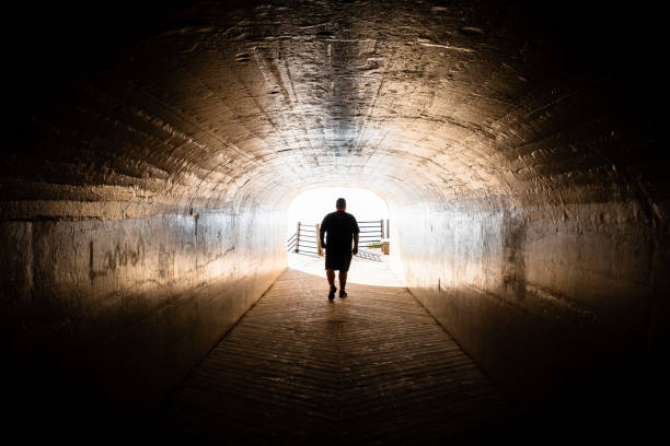 istock silhouette walking in tunnel 1185776374