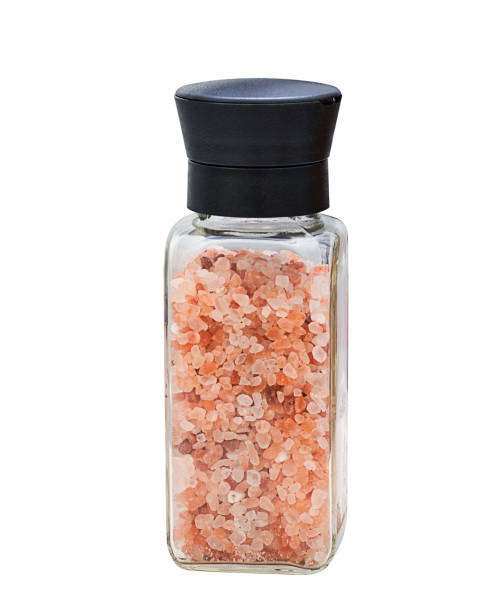 pink Himalayan salt crystals in a glass grinder  on white background