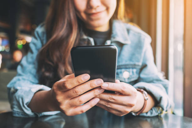 istock a woman holding , using and looking at mobile phone 1185778204