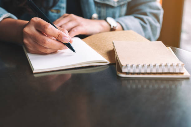 istock a woman writing on a blank notebook on the table 1185778243