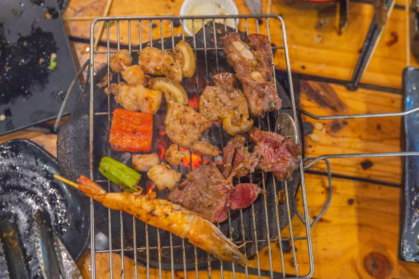гриль маринованного мяса и креветок на пылающей угольной плите - barbecue beef close up multi colored стоковые фото и изображения