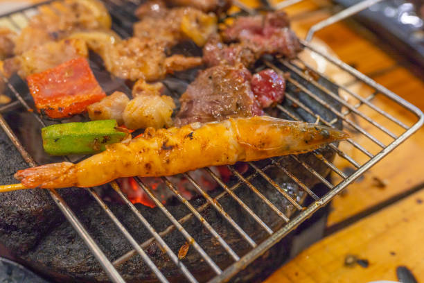 креветки и ассортимент мясной гриль на пылающей угольной плите - barbecue beef close up multi colored стоковые фото и изображения