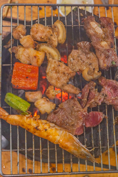 вертикальная фотография мяса и креветок на угольной плите для гриля - barbecue beef close up multi colored стоковые фото и изображения