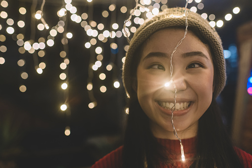 an asian chinese young woman making funny face with string light during the christmas dinner party
