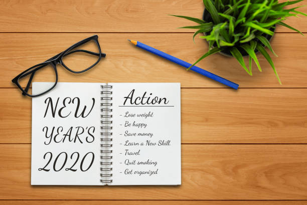 istock New Year Resolution Goal List 2020 - Business office desk with notebook written in handwriting about plan listing of new year goals and resolutions setting. 1185804814