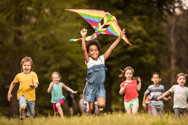 stor grupp av glada barn som springer med en drake på våren. - flying kite bildbanksfoton och bilder