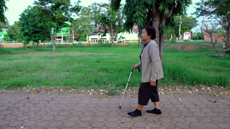 senior woman walking with walking stick in the park