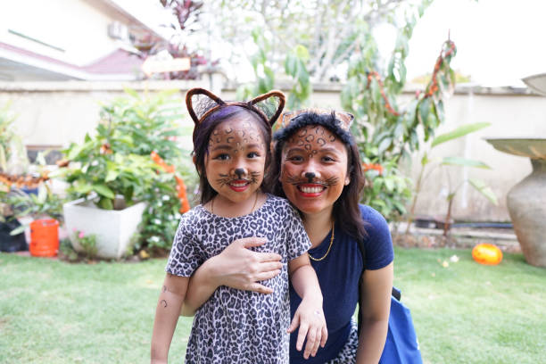 A little girl and her mother dresses up and make-up as cheetahs. stock photo