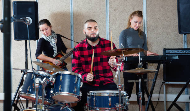 istock Expressive drummer with his bandmates practicing in rehearsal room 1185817201