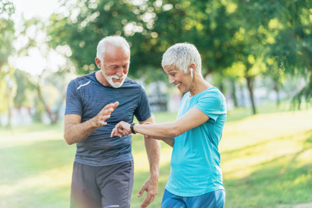 Senior couple using sports technologies Senior couple using sports technologies in the park pedometer stock pictures, royalty-free photos & images