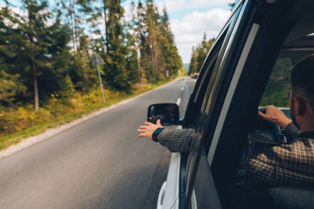 istock man catch wind with hand wile driving car straight highway 1185831070