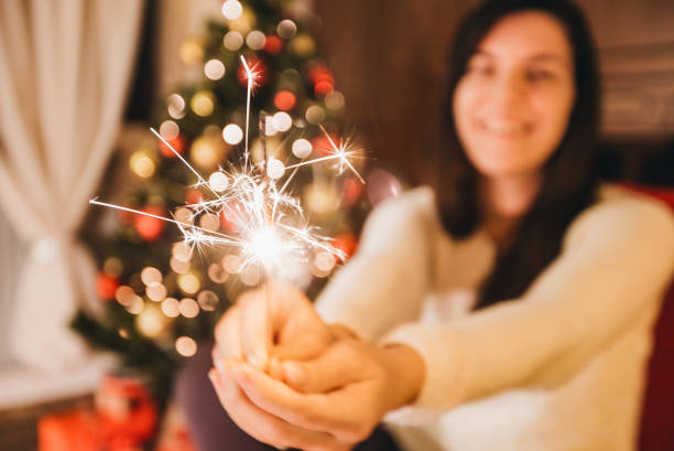 istock Woman holding sparkler next to Christmas tree 1185832332