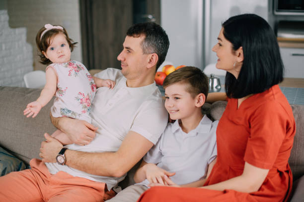 istock Happy family sitting on couch at home 1185834794