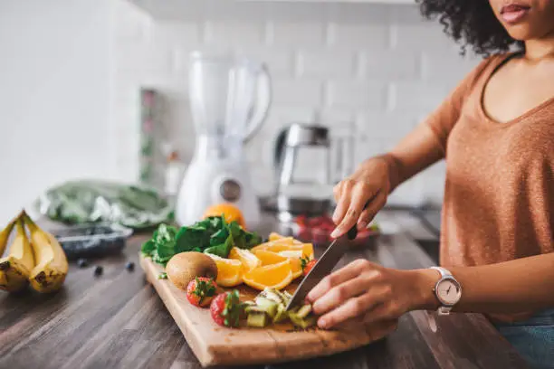 Cropped shot of a young woman making a healthy snack with fruit at home