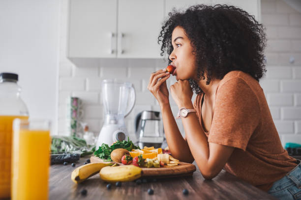 人の健康は食べ物次第 - women eating fruit food ストックフォトと画像