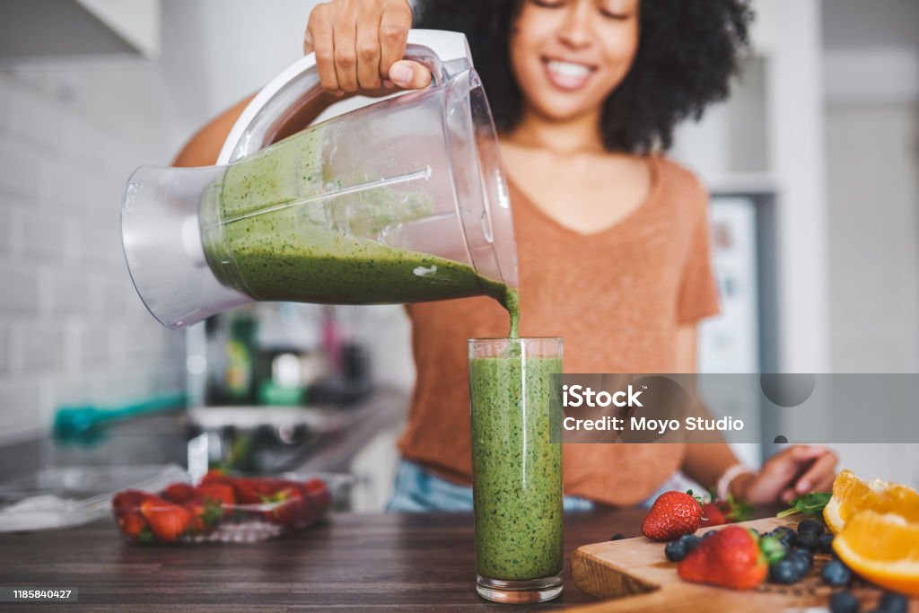 Packed with a huge vitamin punch Shot of a young woman making a healthy smoothie at home Healthy Eating Stock Photo