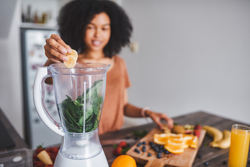 Shot of a young woman making a healthy smoothie at home