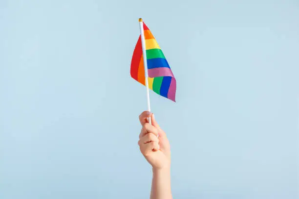 Gay flags in women's hand on grey background