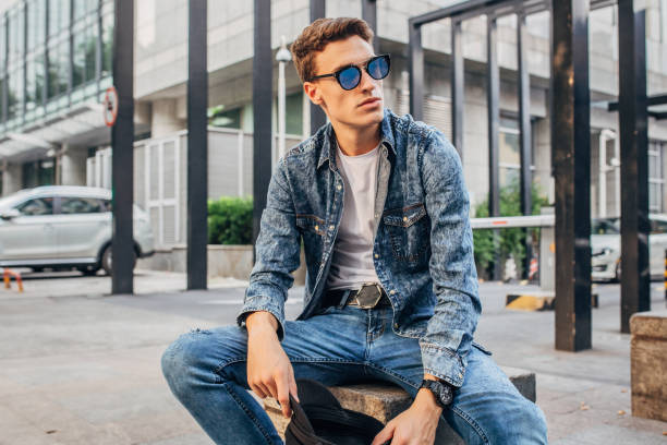 Modern young guy sitting outdoors Modern young man sitting outdoors. double denim stock pictures, royalty-free photos & images