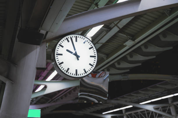 White simple clock hanging on pole in railway station