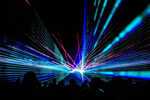 Photo of Colorful laser show nightlife club stage with party people crowd