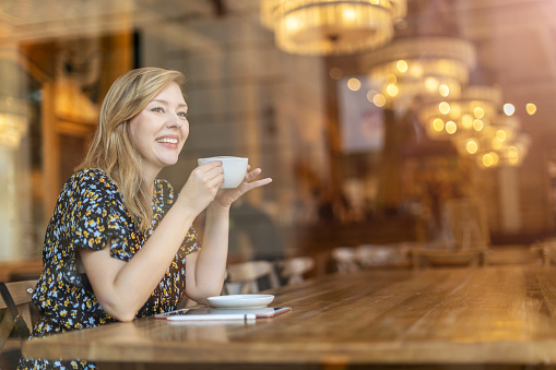 Beautiful young woman drinking cappuccino at cafe