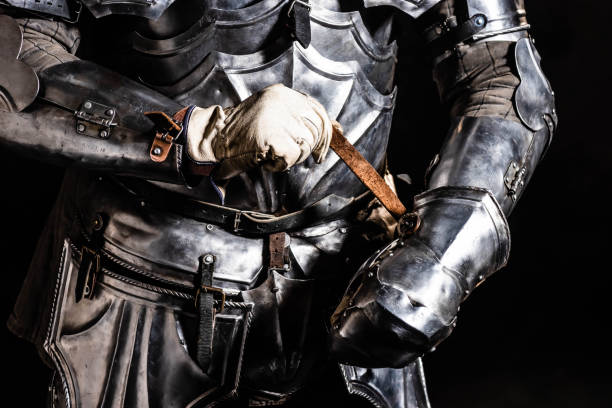 istock cropped view of knight fixing armor isolated on black 1185855406
