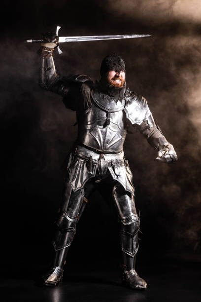 istock handsome knight in armor holding sword and fighting on black background 1185855417