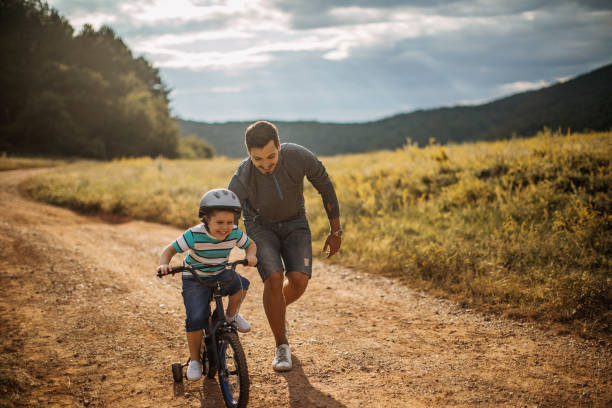 father teaches son to ride a bike - 3494 imagens e fotografias de stock