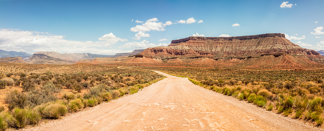 Rock formations surrounding a winding dirt road in southern Utah, USA.