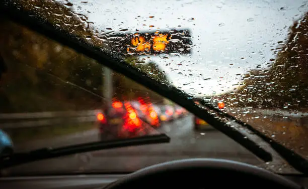Wipers clearing rain, and roads busy with traffic as the light fades on a winter commute.