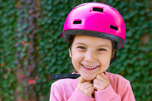 A child wearing a helmet puts on protective knee pads from falls for roller skating on city tracks.