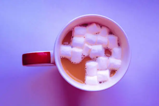 Photo of Coffee with marshmallows in mug in neon light, top view.