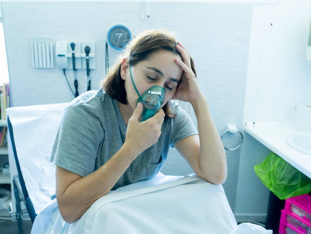Young attractive woman with oxygen mask looking sad and worried at hospital bed in clinic bedroom in lung cancer diagnose, smoking and respiratory disease and anti tobacco advertising campaign. Young attractive woman with oxygen mask looking sad and worried at hospital bed in clinic bedroom in lung cancer diagnose, smoking and respiratory disease and anti tobacco advertising campaign. hospital depression sadness bed stock pictures, royalty-free photos & images