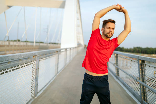 istock Beautiful male runner stretching before workout, fit man doing exercises outdoors 1185869633