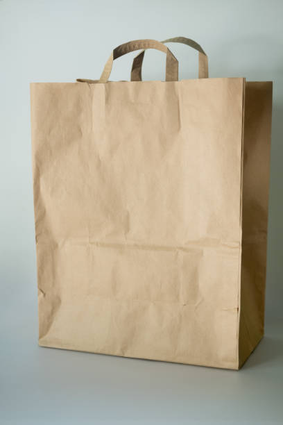 istock Brown paper bag on a white background. Concept of eco-friendly packaging, minimal composition. 1185873266