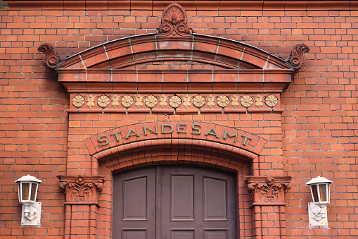 A red brick building with front door and two white wall lights on the side