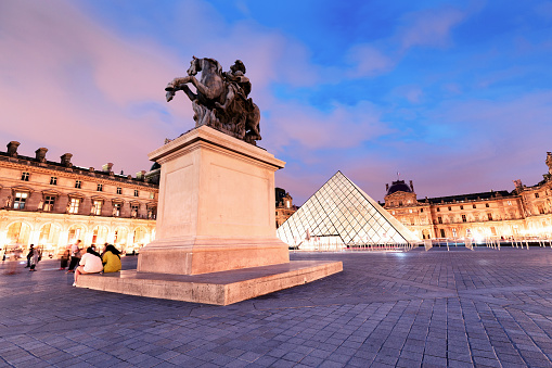 26 July 2019, Paris, France: Equestrian statue of king Louis XIV in the courtyard of the Louvre museum at evening time