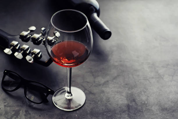 istock Guitar and high glass with red wine on a stone background. 1185877327