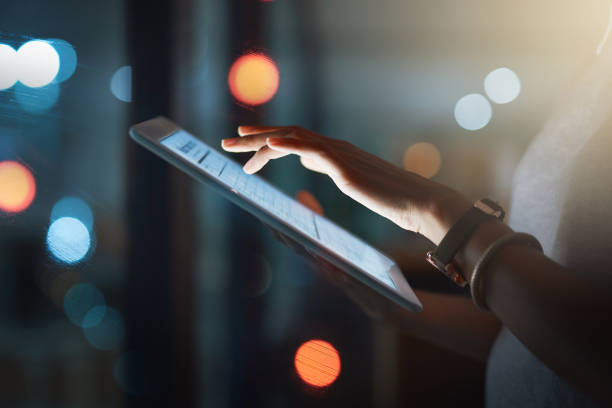 Staying in the loop is compulsory Cropped shot of an unrecognizable businesswoman using a digital tablet while working late defocused woman stock pictures, royalty-free photos & images