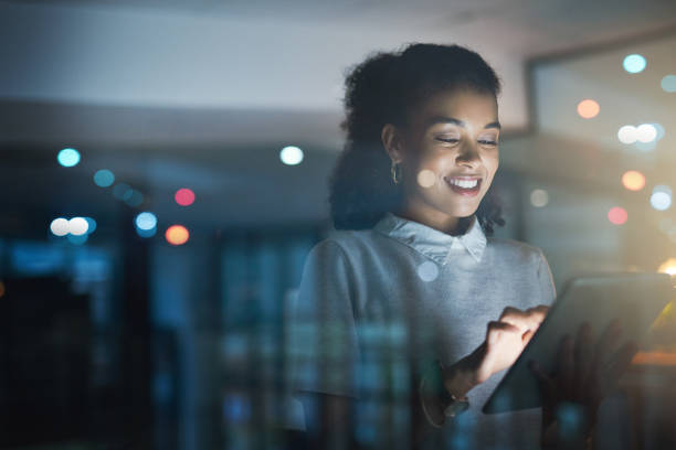 There's no better way to stay organized Shot of a young businesswoman using a digital tablet while working late in her office office window night stock pictures, royalty-free photos & images