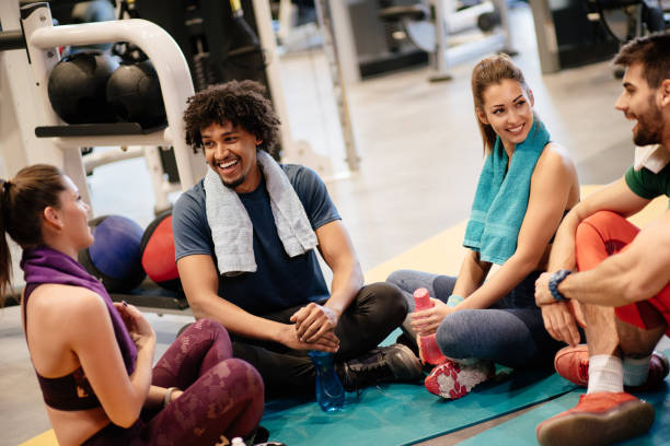 istock Young cheerful people resting from exercising at gym and communicating 1185879538
