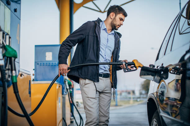 guy gießt kraftstoff in fahrzeug an der tankstelle - station stock-fotos und bilder