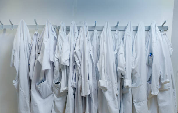 White lab coats hanging from hook at laboratory Lab coats hanging from hooks at laboratory. White workwear are against wall. It is in place of research. hook of holland stock pictures, royalty-free photos & images