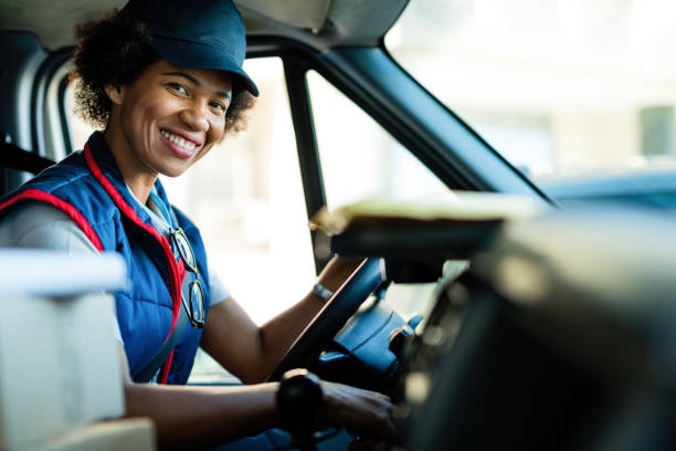 バンを運転する幸せなアフリカ系アメリカ人の配達女性。 - postal worker ストックフォトと画像