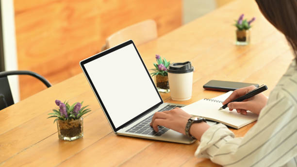 istock Cropped shot female using isolated screen laptop and writing notebook. 1185885143