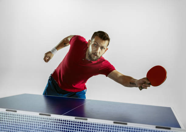 istock Young man playing table tennis on white studio background 1185887559