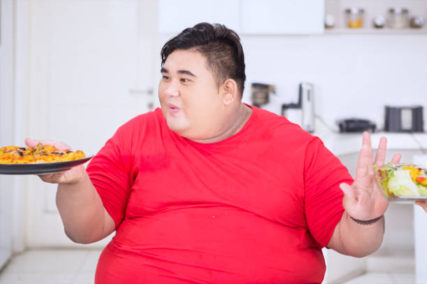 istock Young fat man choosing pizza in the kitchen 1185893808