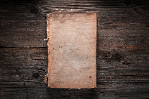 Closed book on vintage wooden background.  Old book on the wooden table. Closed book with empty cover laying on wooden table.